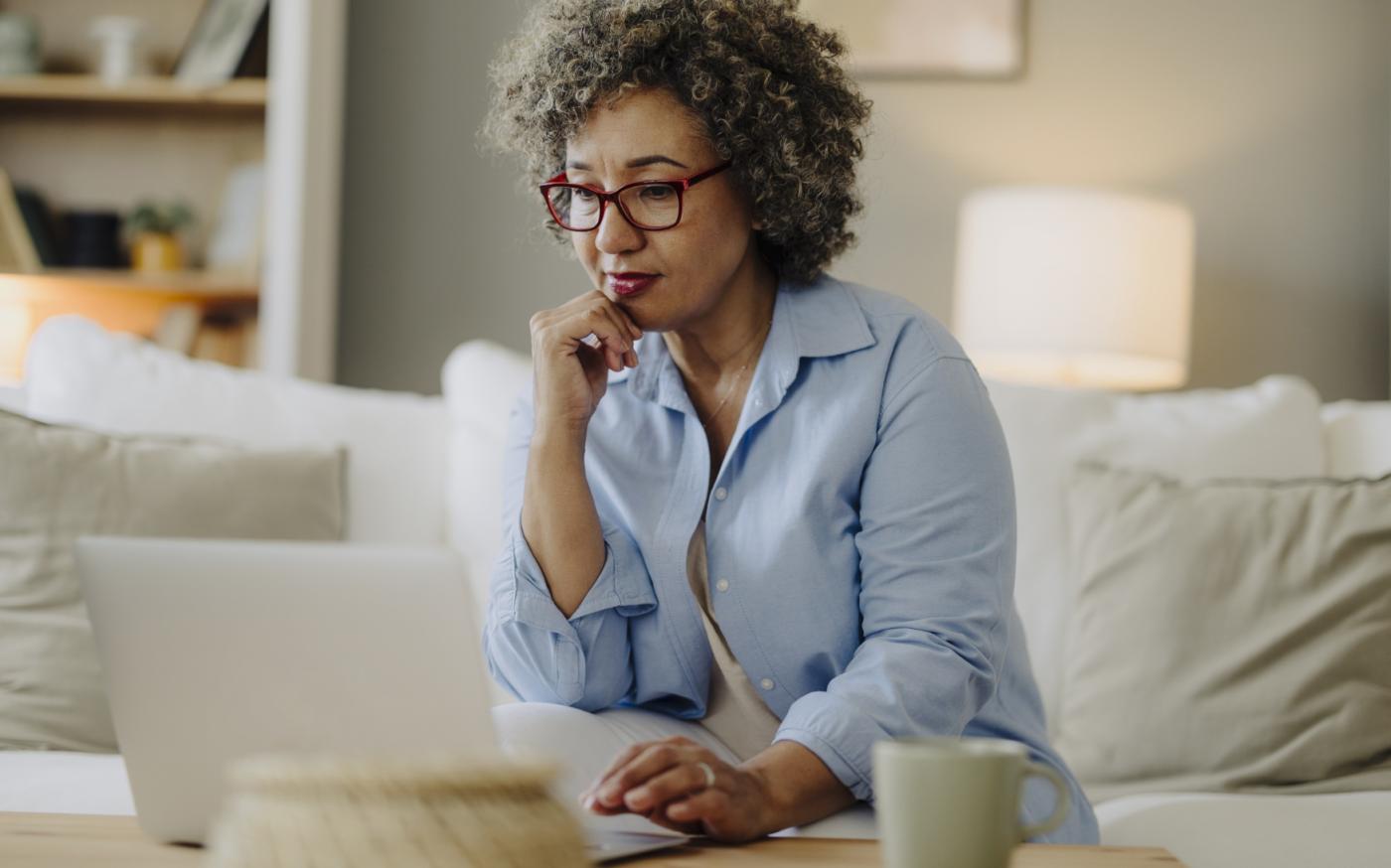 Femme qui réfléchit pendant qu'elle utilise son ordinateur portable