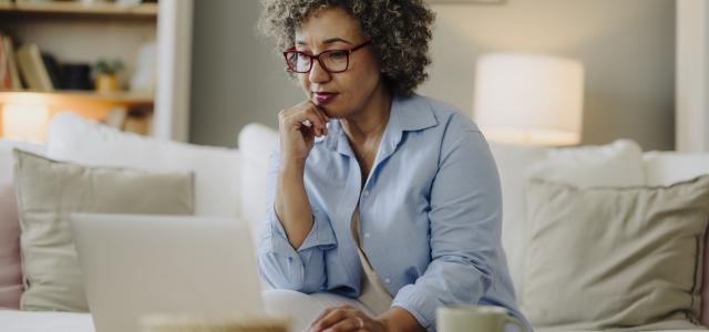Femme qui réfléchit pendant qu'elle utilise son ordinateur portable